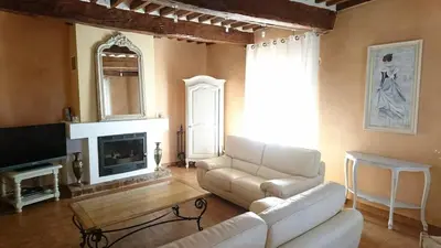 a living room with a white couch and a tv at Grande maison de village - solarium et terrasse in Saint-Martin-de-Castillon