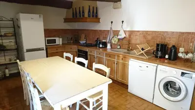 a kitchen with a table and a washing machine at Grande maison de village - solarium et terrasse in Saint-Martin-de-Castillon