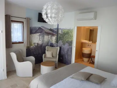 a bedroom with a bed and two chairs and a chandelier at Les Mazets du Luberon in Puget