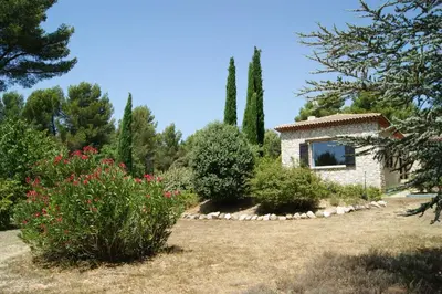a garden with a building and some bushes and trees at Les Mazets du Luberon in Puget