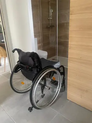 a wheelchair sitting in a room with a shower at l'Esquirou in Malemort-du-Comtat