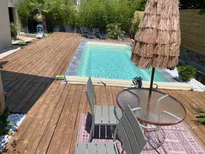 a deck with a table and chairs next to a swimming pool at l'Esquirou in Malemort-du-Comtat