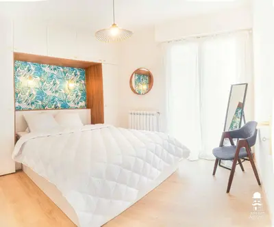 a white bedroom with a large bed and a chair at Le Cézanne in Aix-en-Provence