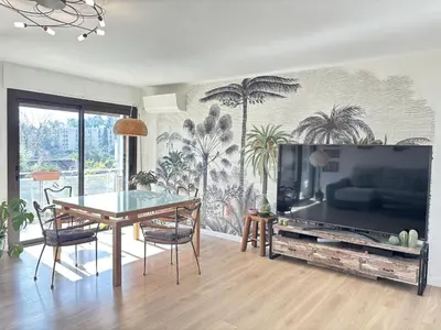 a living room with a table and a large screen television at Les Cerisiers in Aix-en-Provence