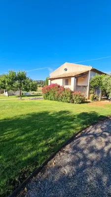 a house with a grass yard and a driveway at Domaine des Hauts de Riganel in La Bastide-des-Jourdans