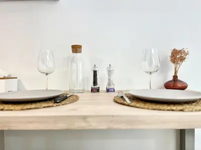 a table with two white plates and wine glasses at Lou Miradou 2 - Vieux village médiéval, Cosy, Clim, 2 personnes in Miramas