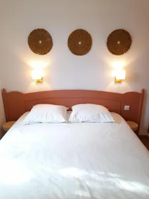 a bedroom with a white bed with two pillows at Le Mazet des Jasmins in Gordes
