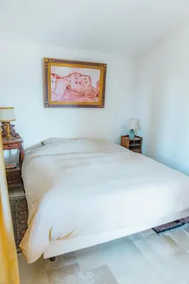 a white bed in a bedroom with a picture on the wall at Maison de charme avec piscine chauffée à Gordes in Gordes