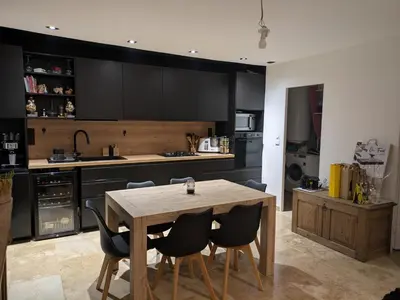 a kitchen with a wooden table and black cabinets at Maison A proximité d'Avignon et site touristique in Avignon