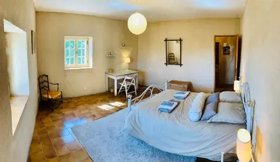 a bedroom with a bed and a desk in a room at Provencal farmhouse in Luberon's heart with pool in La Bastide-des-Jourdans