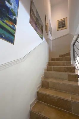 a staircase in a house with paintings on the wall at La Villa Plein Soleil in LʼIsle-sur-la-Sorgue