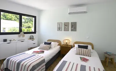 two beds in a room with white walls and a window at La Villa Plein Soleil in LʼIsle-sur-la-Sorgue