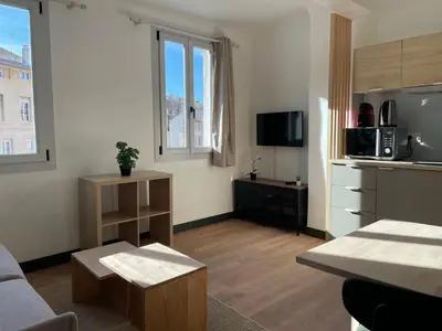 a living room with a couch and a kitchen at Studio climatisé plein centre ville 2ème ETAGE in Aix-en-Provence