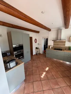 a large kitchen with a tiled floor and white cabinets at Mas de charme provencal in Cavaillon
