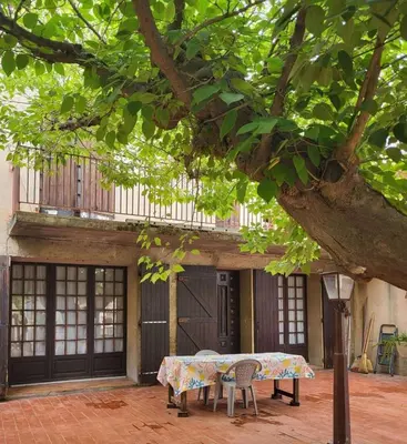 a table and chairs under a tree in front of a building at Maison Provençale Vue Étang & Charme Médiéval in Saint-Chamas