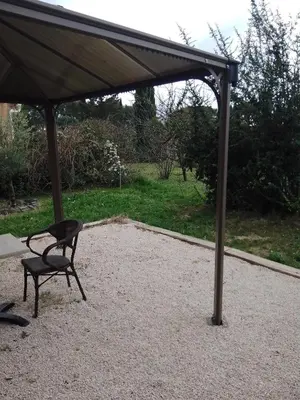 a black chair under an umbrella on a gravel patio at Studio à la campagne in Éguilles