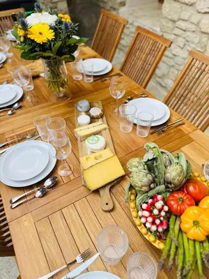 a wooden table topped with plates of food and vegetables at Exceptionnel - Couvent entièrement rénové - classé Patrimoine - Piscine, au calme et à 100 m du coeur de l'Isle in LʼIsle-sur-la-Sorgue