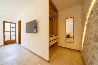 a hallway with a wall with a tv and a mirror at Exceptionnel - Couvent entièrement rénové - classé Patrimoine - Piscine, au calme et à 100 m du coeur de l'Isle in LʼIsle-sur-la-Sorgue