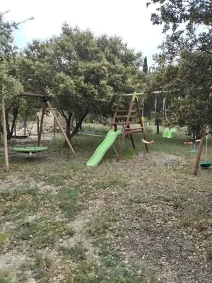 a playground with a green slide and swings at Lou mazet in La Roque-sur-Pernes