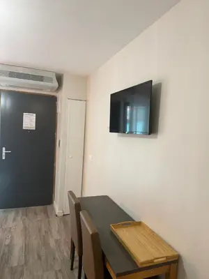 a room with a table and a television on a wall at 119 Sous le ciel de Provence - Aix in Éguilles