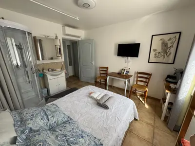a bedroom with a bed and a table and chairs at Chez DOMI in LʼIsle-sur-la-Sorgue