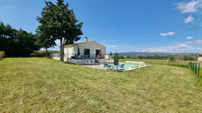 a small white house with a large grass field at Lou Miradou in Maubec