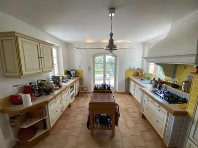 a kitchen with white cabinets and a table in it at Le Mas de Quatremonts - Your refuge in Provence in Bonnieux