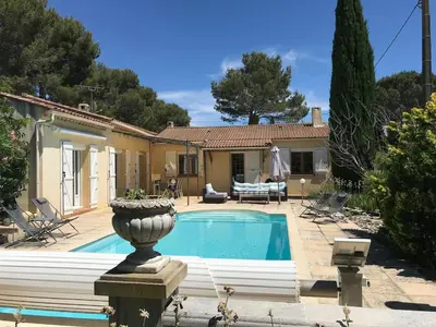 a villa with a swimming pool in front of a house at Maison provençale familiale avec piscine - 6 personnes in Lambesc