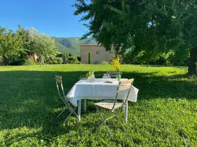 a table with a white tablecloth and two chairs in the grass at Bright Villa In The Heart Of Luberon in Céreste