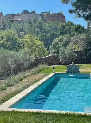 a swimming pool in a yard with a castle in the background at Bohemian House Overlooking Roussillon in Roussillon