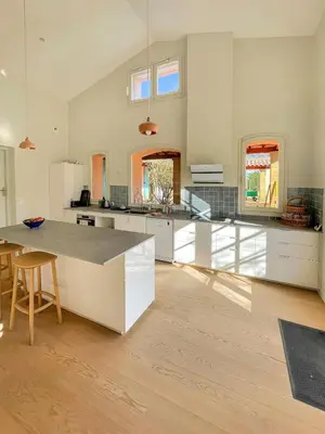 a large kitchen with white cabinets and a table at Grande maison de famille rénovée, vue sur Sainte Victoire in Venelles