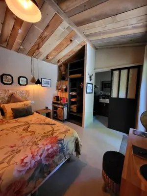 a bedroom with a bed and a desk and a kitchen at le cabanon du clos in LʼIsle-sur-la-Sorgue