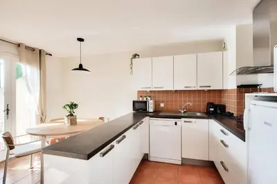 a kitchen with white cabinets and a sink and a table at Village Pont Royal en Provence - maeva Home - Maison climatisée 4 pièces 6 personnes - Sélection - super Home MAE-0411 in Mallemort