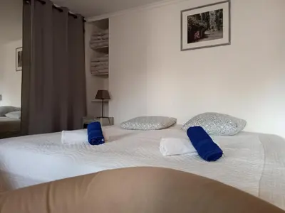 a large white bed with blue pillows on it at Gîte Lavande vue Luberon 33 hectares piscine Spa Sauna au cœur de Provence in Saumane-de-Vaucluse