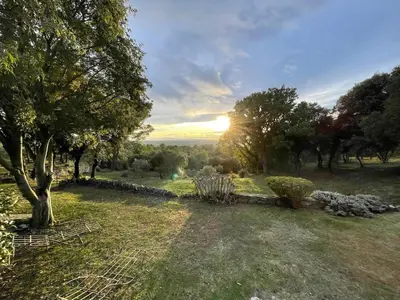 a sunset over a field with trees and a stone wall at Gîte Lavande vue Luberon 33 hectares piscine Spa Sauna au cœur de Provence in Saumane-de-Vaucluse