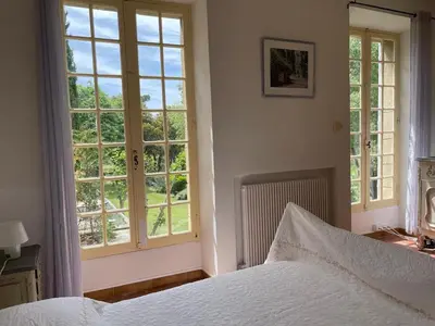 a bedroom with a bed and two windows at Lubéron Gîte Chaleureux 100 m2 piscine jardin in Saumane-de-Vaucluse