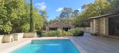 a swimming pool on a wooden deck next to a house at Air-conditioned Stylish Provence Villa in Oppède