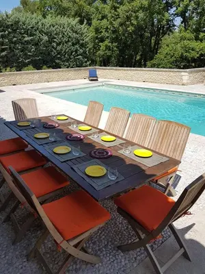 a wooden table with chairs next to a swimming pool at Air-conditioned Stylish Provence Villa in Oppède