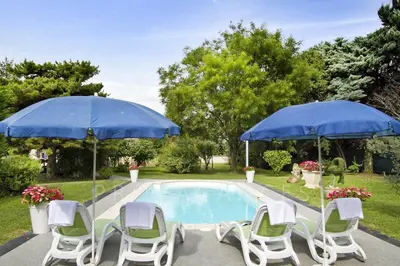 two blue umbrellas and chairs next to a pool at MAISON de CHARME in Cavaillon