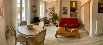 a living room with a table and a red chair at Appartement cosy lumineux et calme in Apt