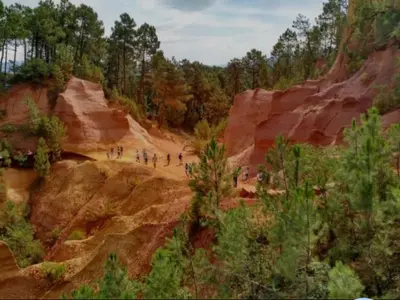 a group of people walking on a dirt road near rocks at Appartement cosy lumineux et calme in Apt