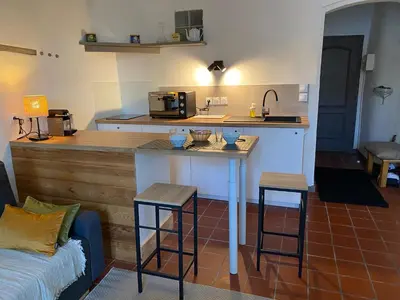 a kitchen with a counter and a table with two stools at Studio avec balcon sur cour in Aix-en-Provence