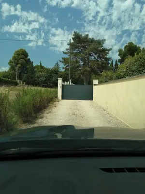 a car driving down a dirt road with a fence at La Sarriette Provençale in Caumont-sur-Durance