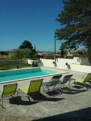a group of chairs sitting around a swimming pool at La Sarriette Provençale in Caumont-sur-Durance