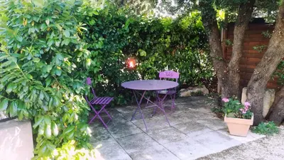 a table and chairs in a garden with a hedge at Villa les Lauriers in Lioux