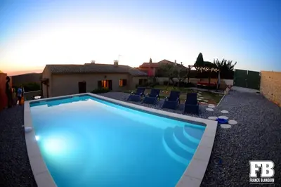 a blue swimming pool with chairs and a house at Le Jardin d'Auguste in Roussillon