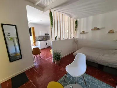 a bedroom with a bed and a white chair at Cosy downtown studio in Apt