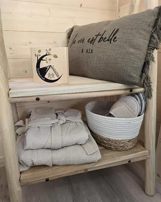 a shelf with towels and a pillow and a basket at La Cabane Aixoise Piscine & Jacuzzi in Aix-en-Provence