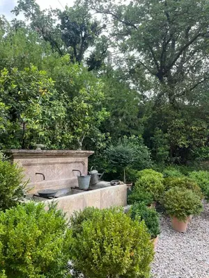a stone fountain in a garden with bushes and trees at Holiday Home in Lourmarin Stunning View of the Château in Lourmarin