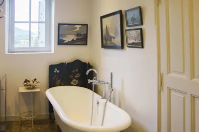 a white bath tub in a bathroom with pictures on the wall at Holiday Home in Lourmarin Stunning View of the Château in Lourmarin